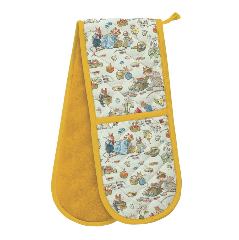 A quilted double oven mitt with a mustard yellow border and lining, featuring a cream-colored patterned panel with a whimsical rabbit and tea-time illustration.