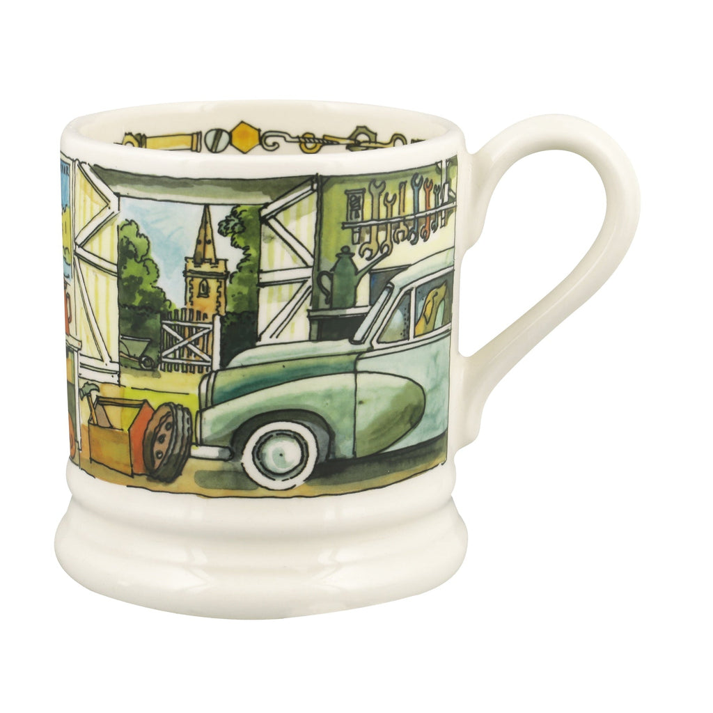 A white ceramic coffee mug featuring a colorful hand-painted illustration of a vintage green car parked in front of a barn with a church steeple in the background.